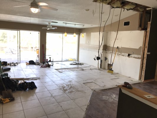 Interior view of a partially renovated living space in Englewood, Florida, featuring exposed drywall, construction tools, and debris, illustrating the drywall repair process by Build Rite Builders.