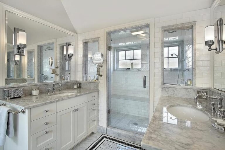 Modern bathroom featuring a stylish shower with glass enclosure, marble countertops, dual sinks, and elegant lighting, ideal for DIY shower renovations in Port Charlotte.