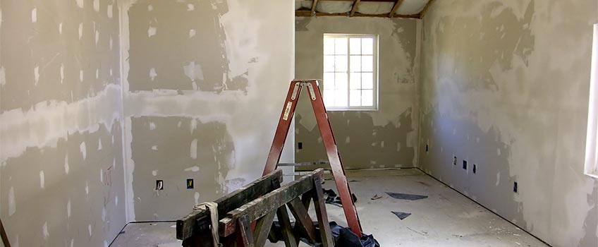 Drywall repair in progress with a ladder, unfinished walls, and construction debris in a room in Port Charlotte, FL.