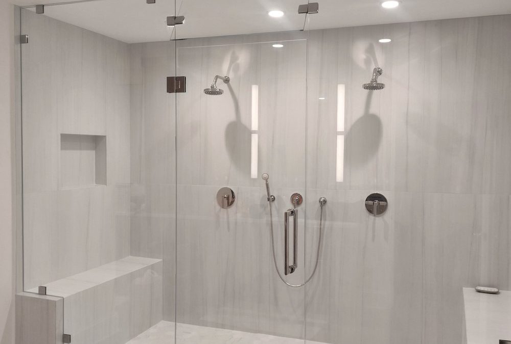 Modern glass shower enclosure with dual showerheads, sleek tile walls, and built-in seating, showcasing contemporary bathroom design trends in Port Charlotte, FL.