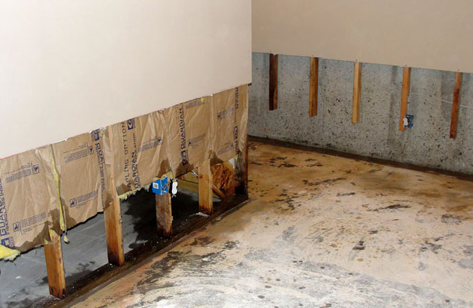 Drywall repair project showing exposed wooden studs and damaged lower wall section in a residential setting in Englewood, Florida.