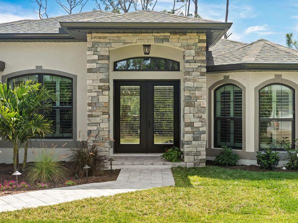 Modern home entrance with stone accents and landscaped front yard in Port Charlotte, Florida, highlighting renovation potential.