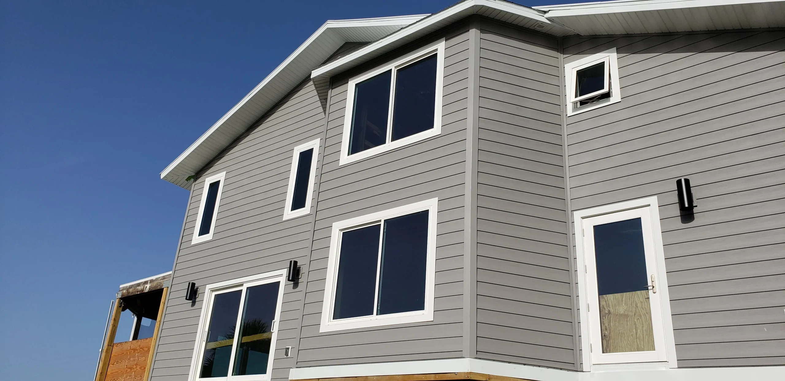 Modern home exterior featuring large windows and a door, emphasizing energy efficiency and aesthetic appeal for door and window installation services.